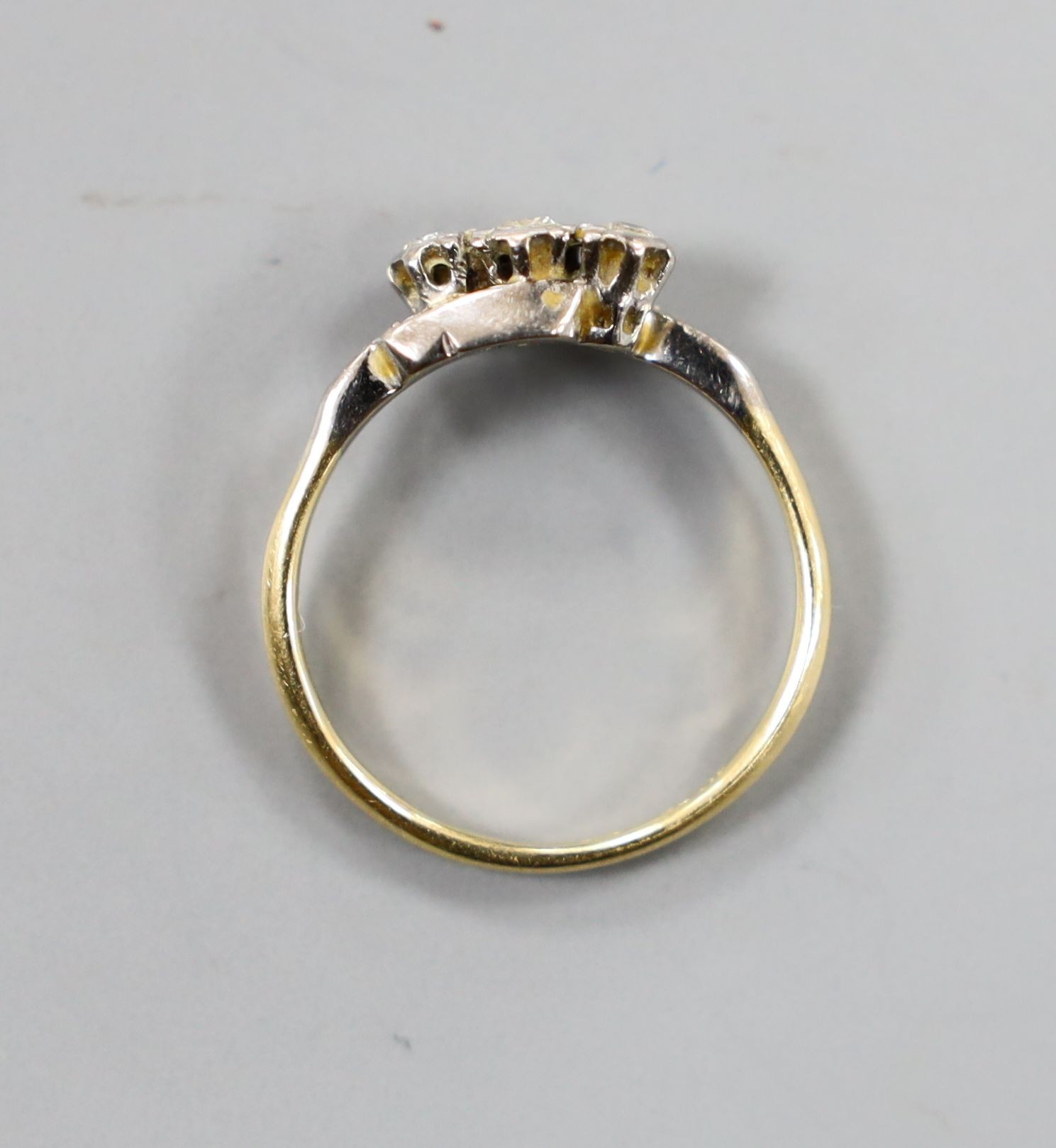 An 18ct, plat and three stone diamond crossover ring, size O, gross 2.4 grams.